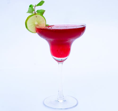 A red cocktail with lime and mint garnish