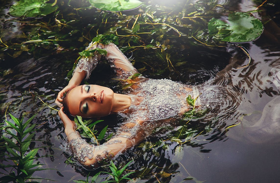 Free Woman In Long Sleeved Dress Surrounded By Water Plants Stock Photo
