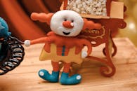 木桌上放着带有爆米花架的充满活力的小丑娃娃玩具，非常适合派对装饰