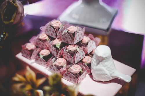Free Beautifully crafted pink flower cupcakes in decorative cases on display with a ceramic bird accent. Stock Photo