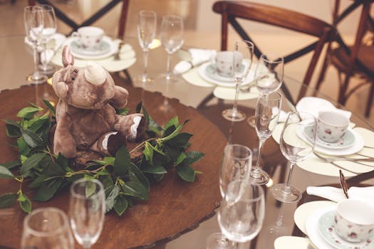 A dining table beautifully set with a plush rhino centerpiece, glassware, and fine china.