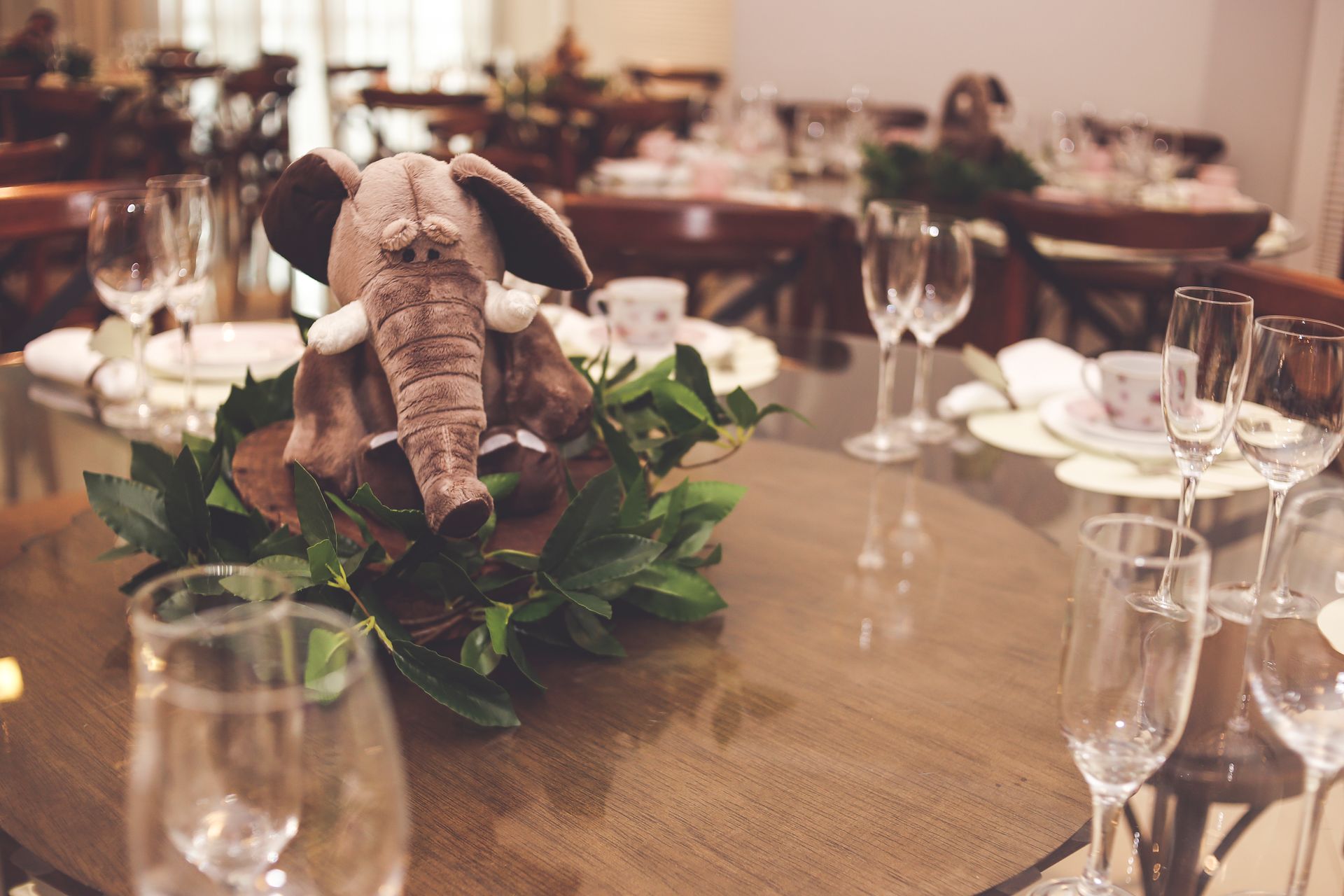 Elegant table setting featuring a plush elephant centerpiece surrounded by greenery.