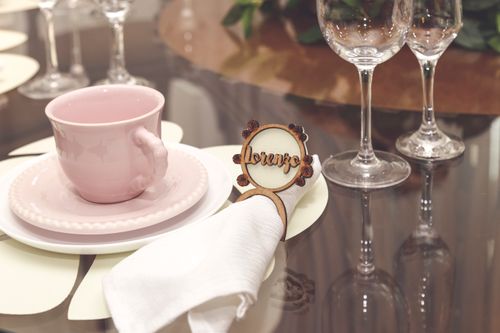Free A stylish and elegant table setting featuring a pink teacup, napkin, and wine glasses on a glass table. Stock Photo