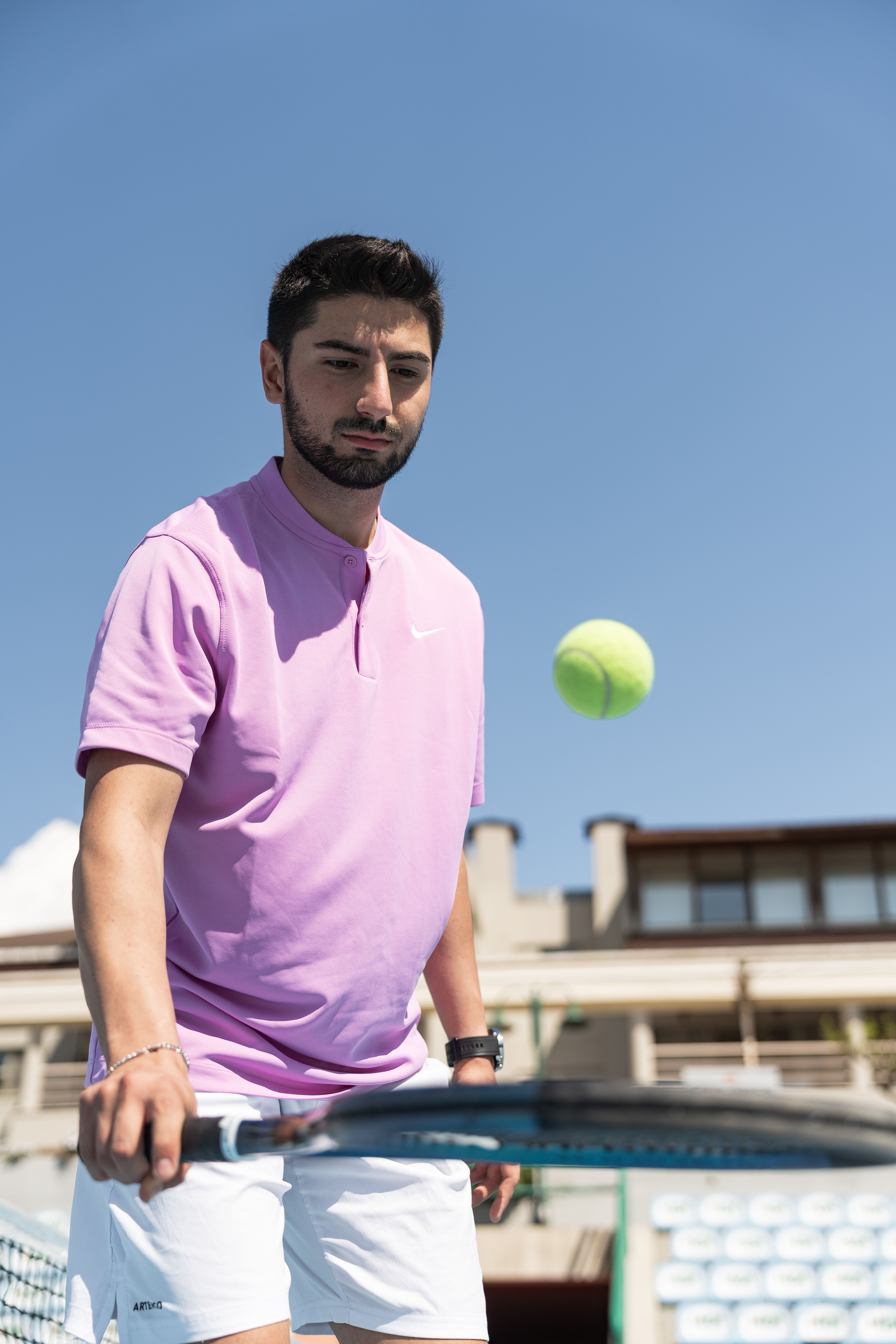 Man in sportswear practicing tennis on a sunny day outdoors.