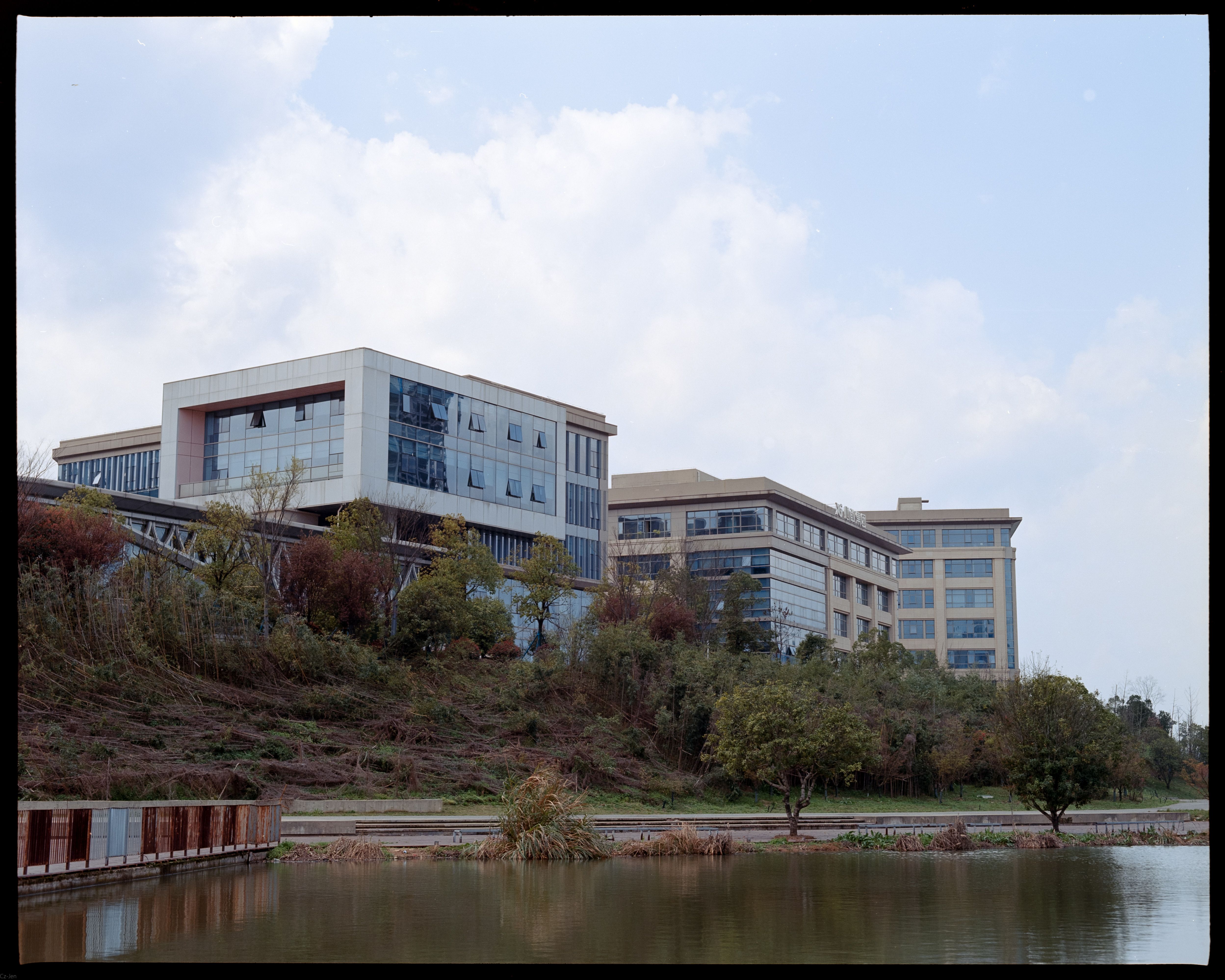 Contemporary buildings reflected in a tranquil lake setting during fall.