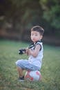 Boy Sitting On Soccer Ball Holding Dslr Camera