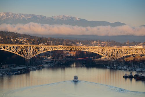 Boat Under Bridge With View of Mountains