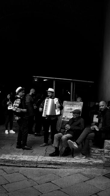 Black and white night street scene with musicians performing.