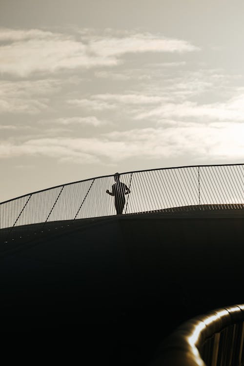 A person walking on a bridge with a skateboard
