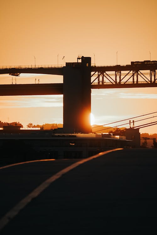 A bridge is silhouetted against the sun