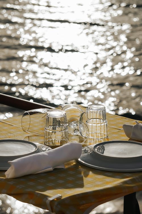 A table set for two with plates and glasses on a yellow tablecloth
