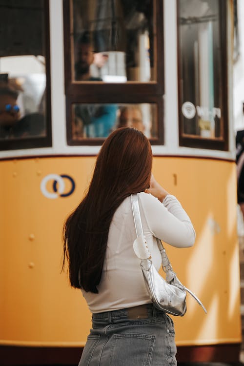 A woman is taking a picture of a yellow tram