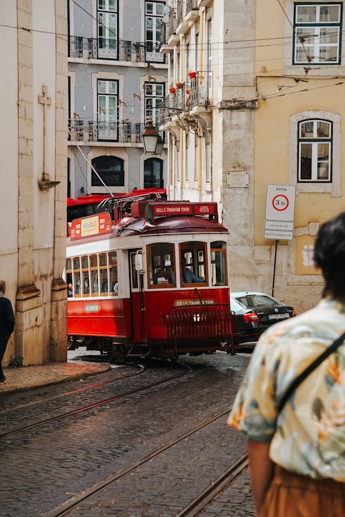 A man walking down a street with a red tram