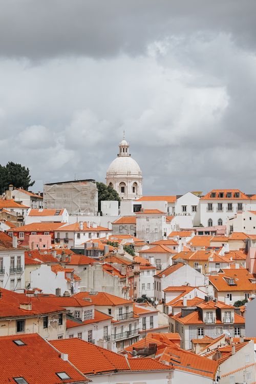 Gratis Vista panoramica dei celebri tetti in terracotta di Lisbona e della sua architettura storica sotto un cielo nuvoloso. Foto a disposizione