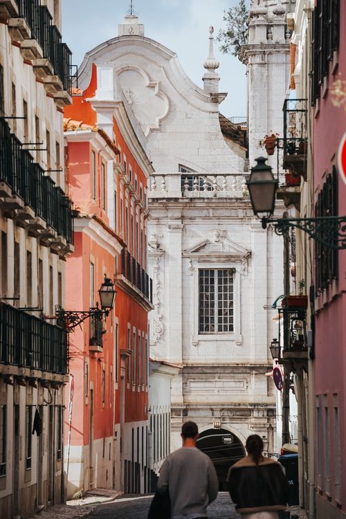 Free A couple walking through charming Lisbon streets with baroque architecture visible. Stock Photo