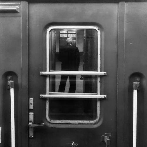 정장에 서있는 남자를 보여주는 거울으로 닫힌 검은 문