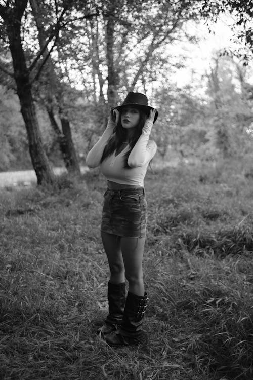 A woman in a hat and boots standing in the woods