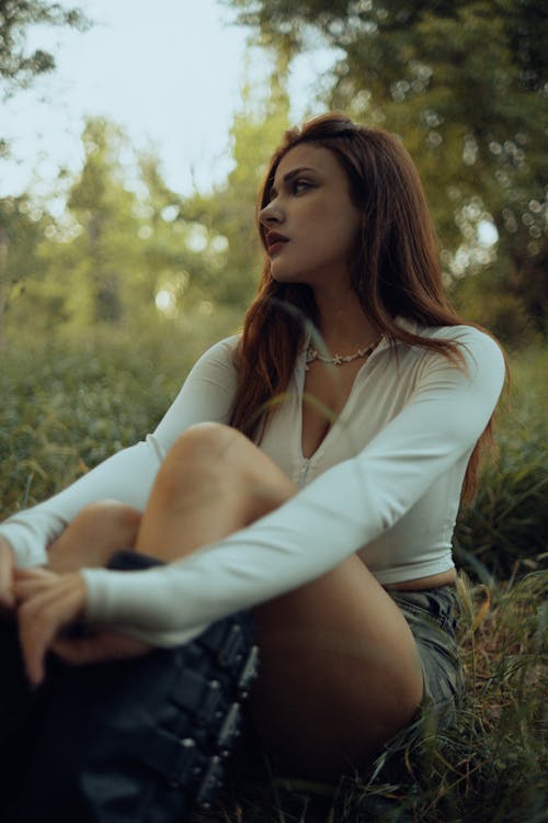 A woman sitting in the grass with her legs crossed