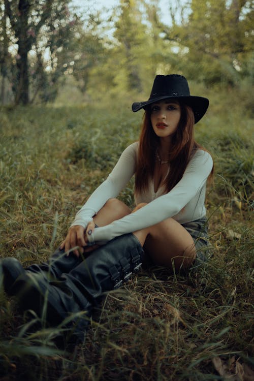 A woman in a hat sitting in the grass
