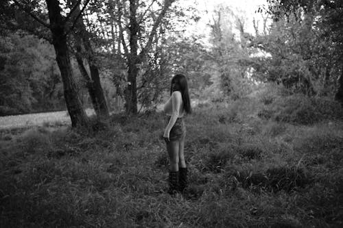 A woman standing in the woods with her back to the camera