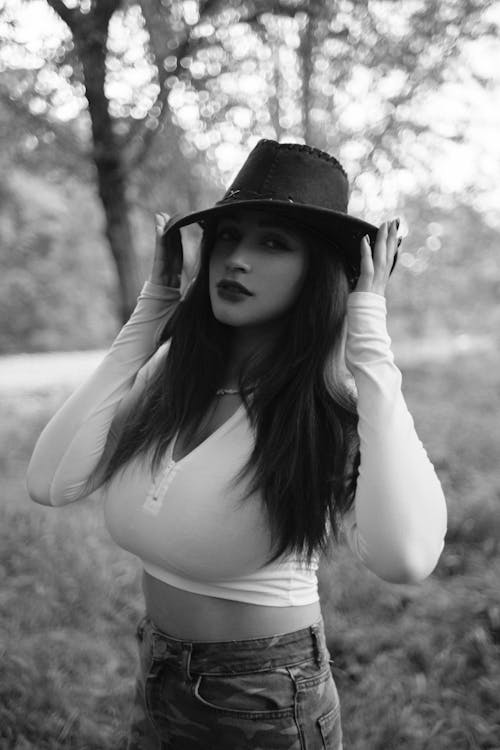 A woman in a hat and jeans posing in the woods