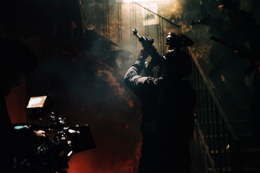 Dramatic silhouette of armed figures in a smoky, dimly lit environment, depicting a military scene.