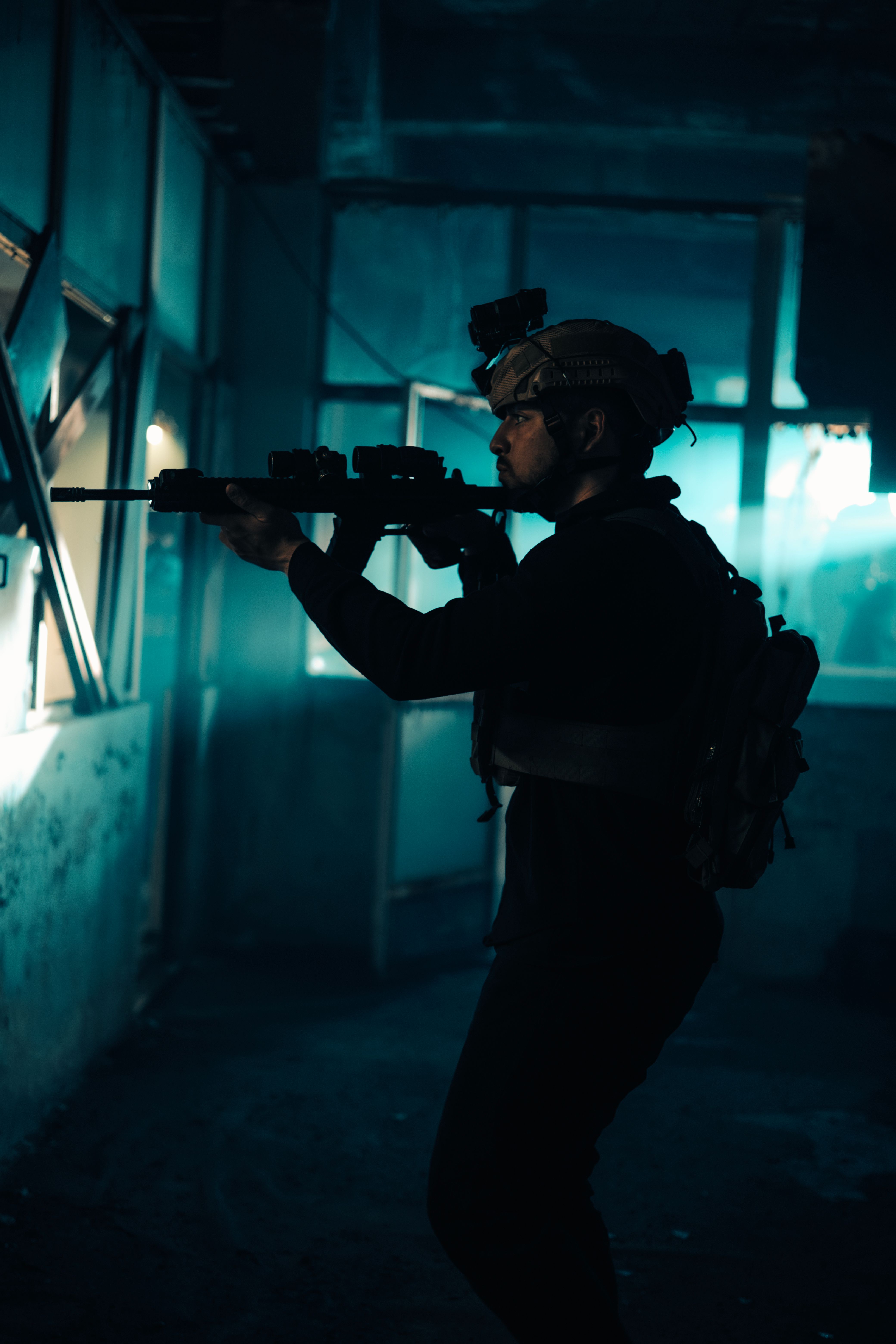 A silhouette of a tactical soldier holding a rifle inside an urban setting, emphasizing action and intensity.