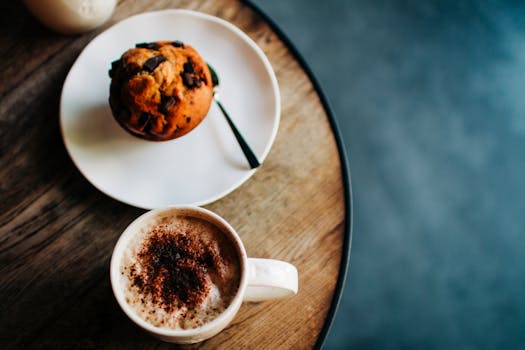 A top view of a chocolate muffin and coffee on a rustic table, creating a cozy café vibe.