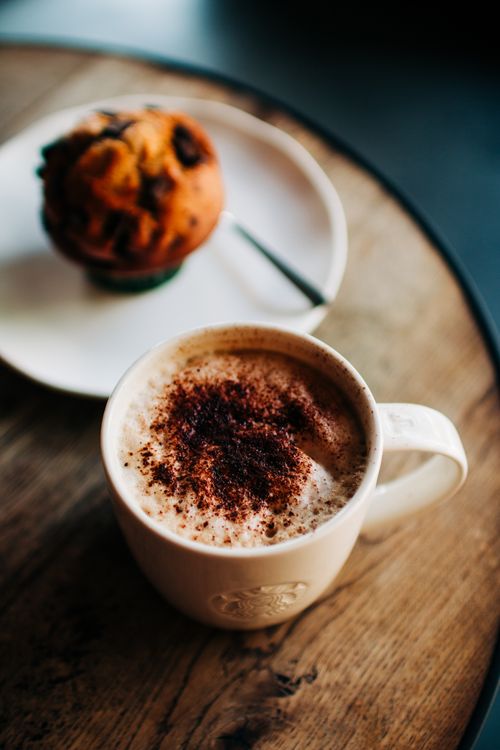 Free Delicious coffee with chocolate sprinkles and a sweet muffin on a rustic wooden table. Stock Photo