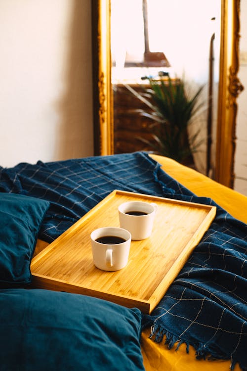 Two cups of coffee on a tray on a bed