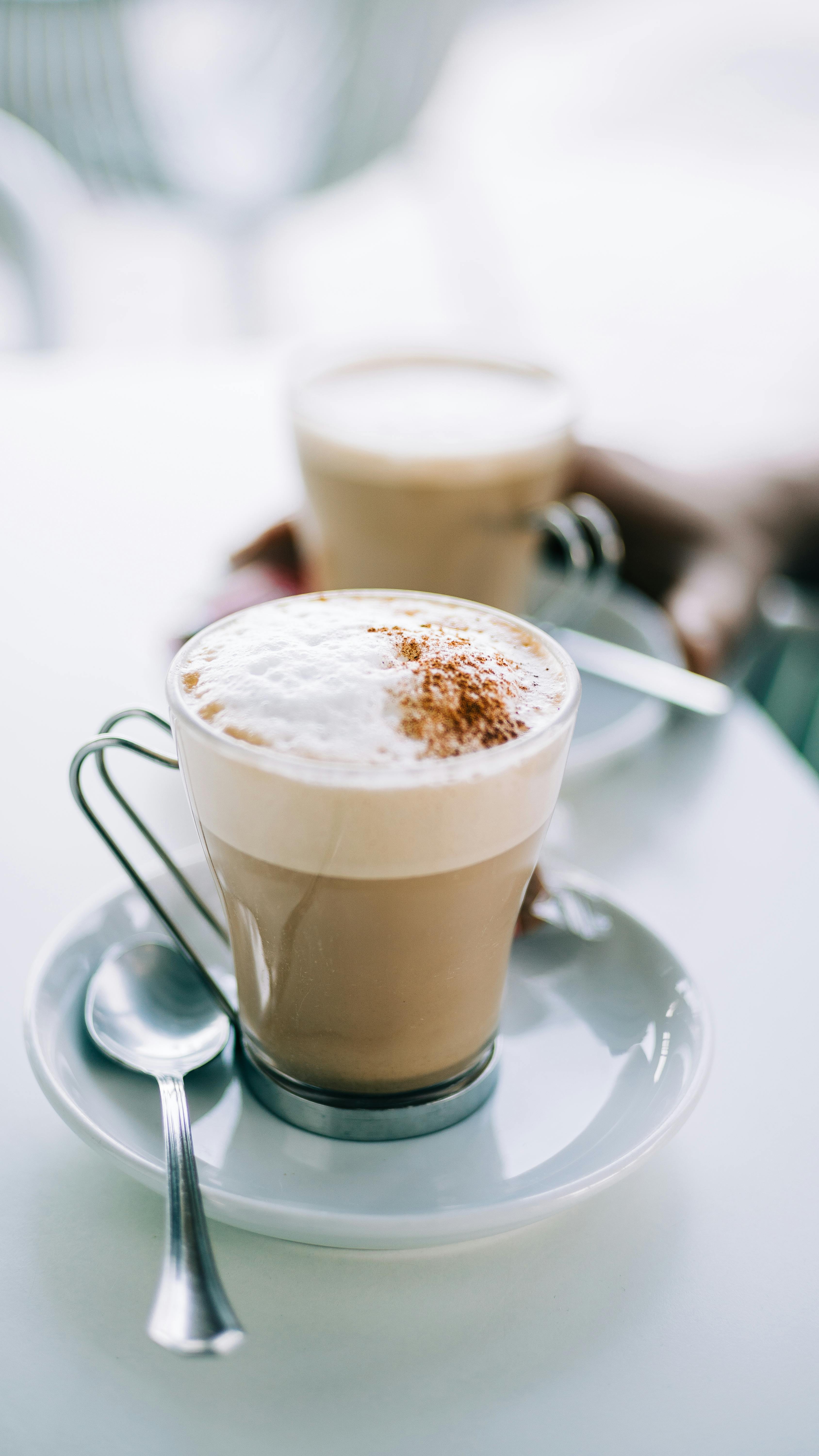 A close-up shot of a cappuccino with cinnamon sprinkles on a white saucer.