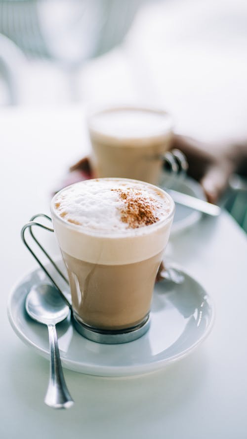 Two cups of coffee on a table with a spoon