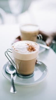 A close-up shot of a cappuccino with cinnamon sprinkles on a white saucer.