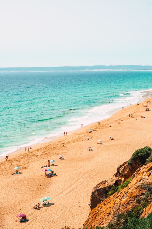 Free A serene aerial shot of a beautiful sandy beach in Spain with turquoise waters and sunbathers. Stock Photo
