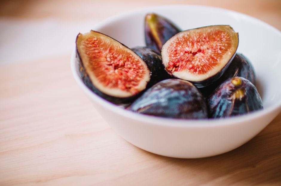 Fresh figs sliced open in a white bowl, displaying interior flesh