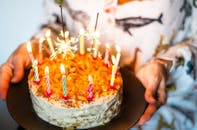A person holding a cake with candles on it