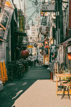 Colorful urban street in Japan filled with signs, bikes, and passersby.