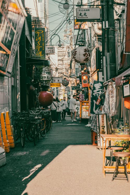 Free Colorful urban street in Japan filled with signs, bikes, and passersby. Stock Photo