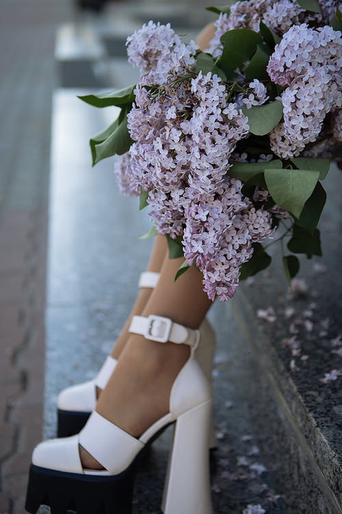 A woman in white heels and purple flowers