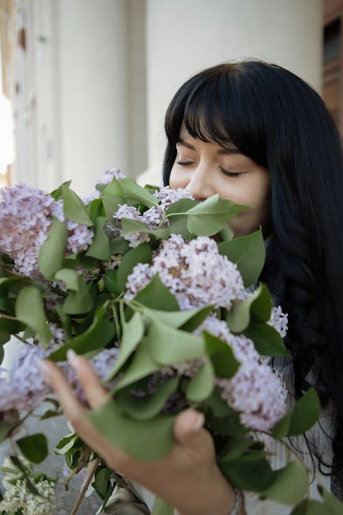 A woman is smelling a bunch of lilas