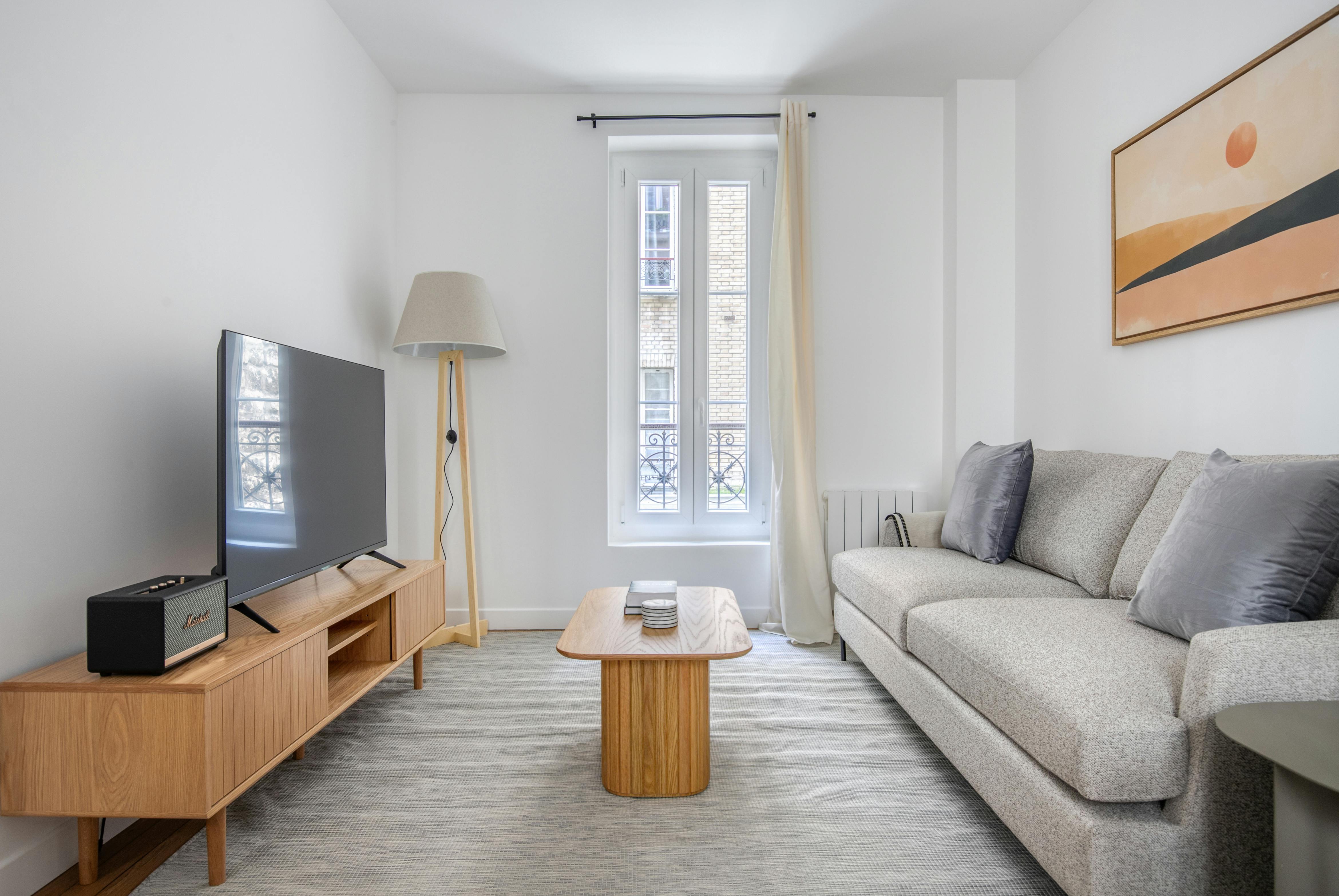 Salon w stylu skandynawskim z ekranem projekcyjnym i szarym tapczanem