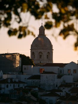 Gorgeous sunset view of Lisbon's dome, framed by foliage, highlighting local architecture.