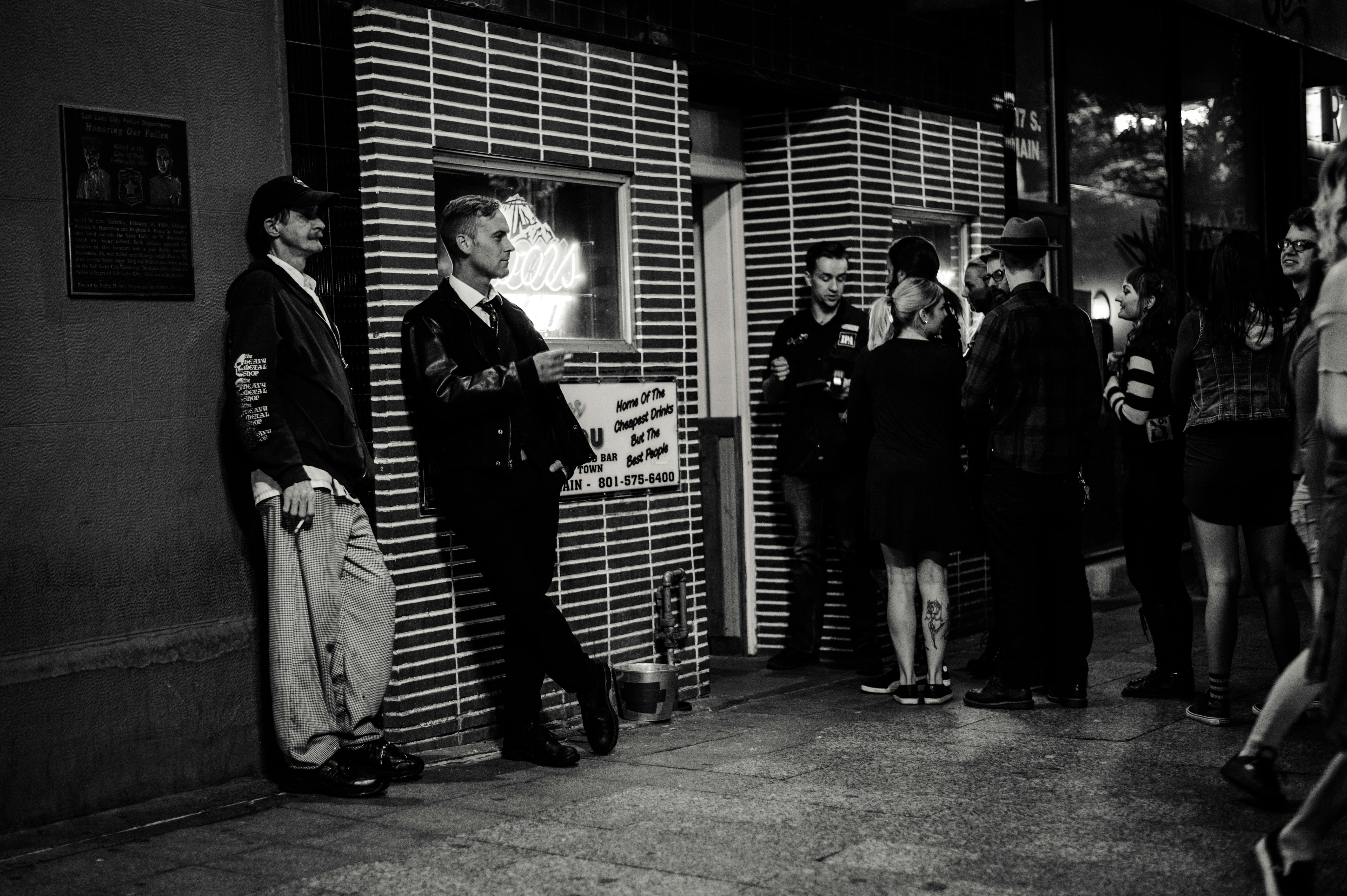 一张黑白照片记录了夜晚酒吧外一群成年人社交的场景