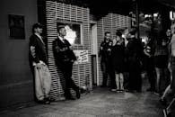 一张黑白照片记录了夜晚酒吧外一群成年人社交的场景