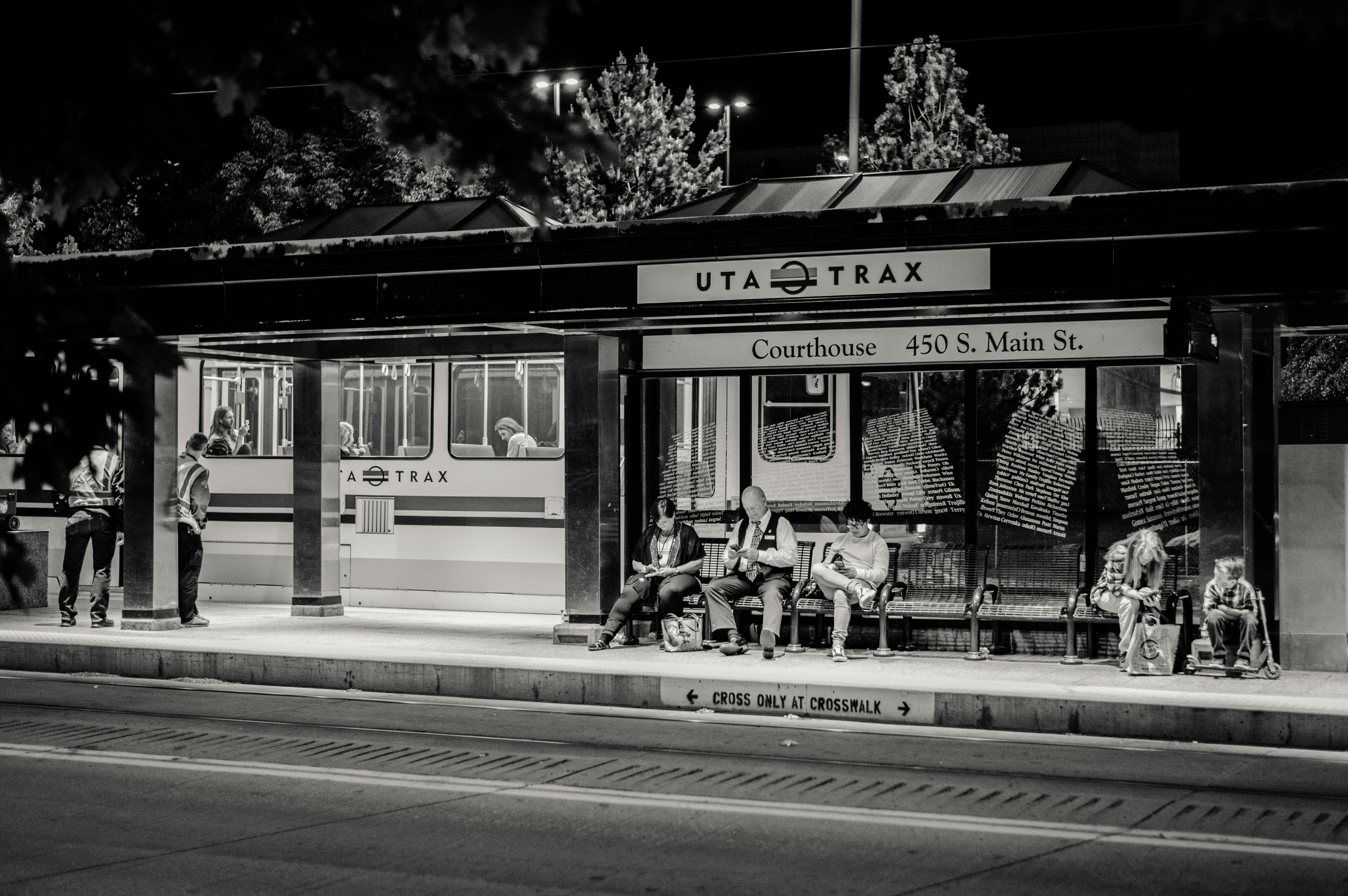 Black and white photo of people at UTA TRAX station in Salt Lake City at night.