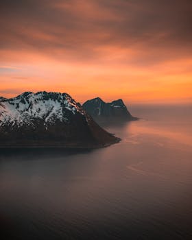 日落时分，天空充满活力，特罗姆斯山脉与大海的鸟瞰图令人惊叹