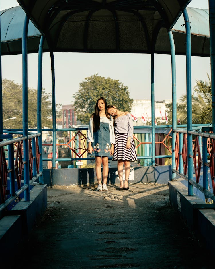 Two Girls Standing Besides Blue Steel Rails