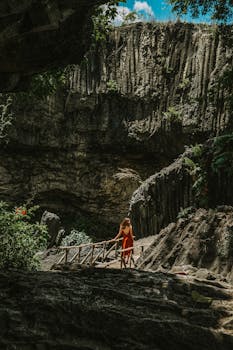 一名妇女走在越南风景优美的洞穴桥上，周围是郁郁葱葱的绿色植被和岩石景观