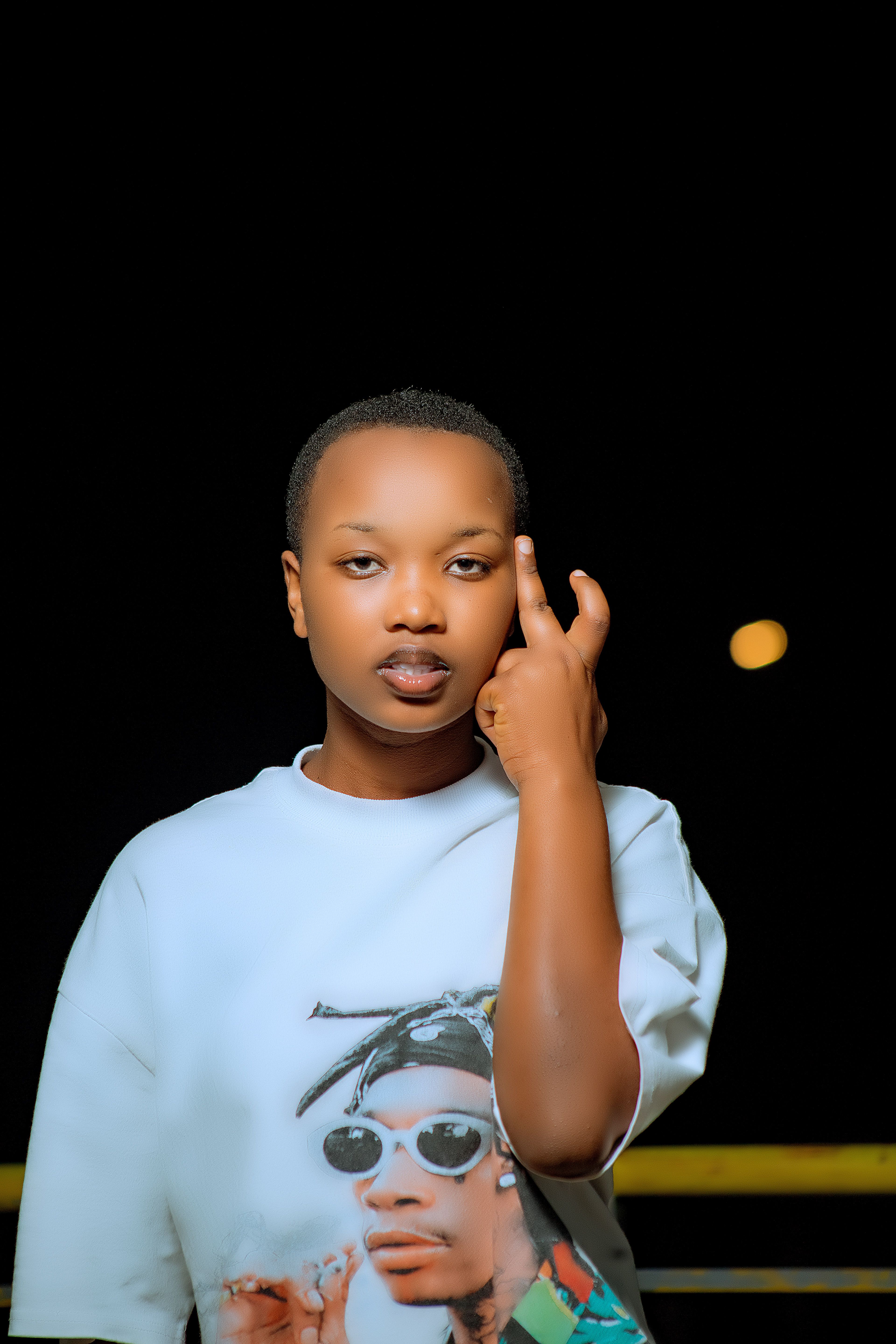 Portrait of a teenager making a gesture at night, wearing a graphic t-shirt.