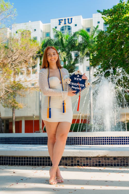 A beautiful young woman in a white dress holding a diploma